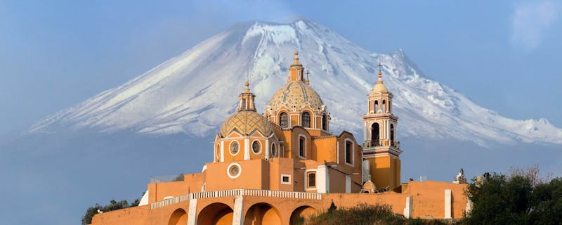 A view over Santuario de la Virgen de los Remedios in Mexico with Popocatépetl volcano in the background.