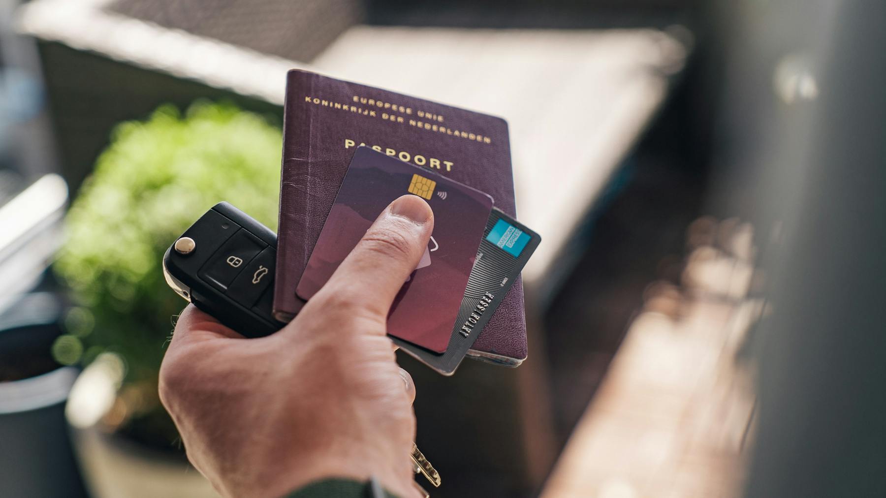 Hombre sosteniendo en su mano izquierda las llaves del auto, el pasaporte, y dos tarjetas de credito