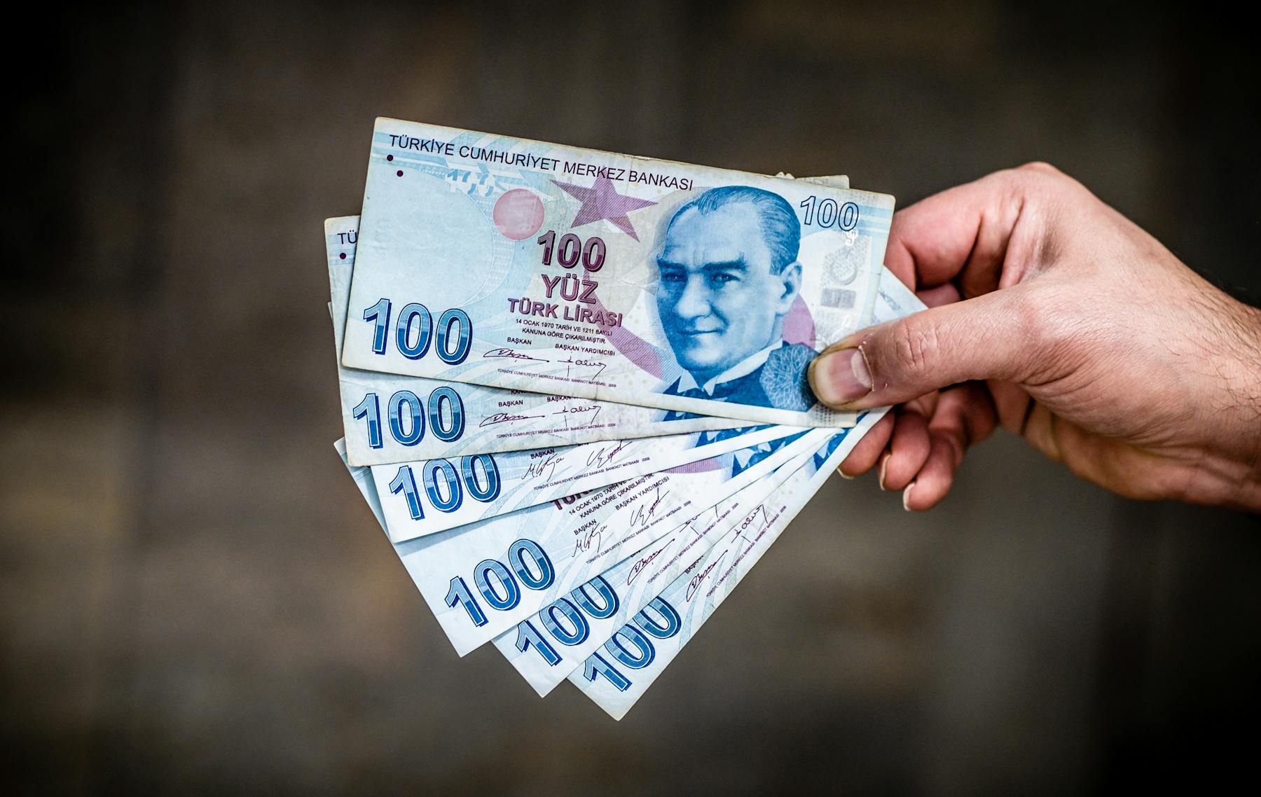 Man's hand holding 600 Turkish lira banknotes.