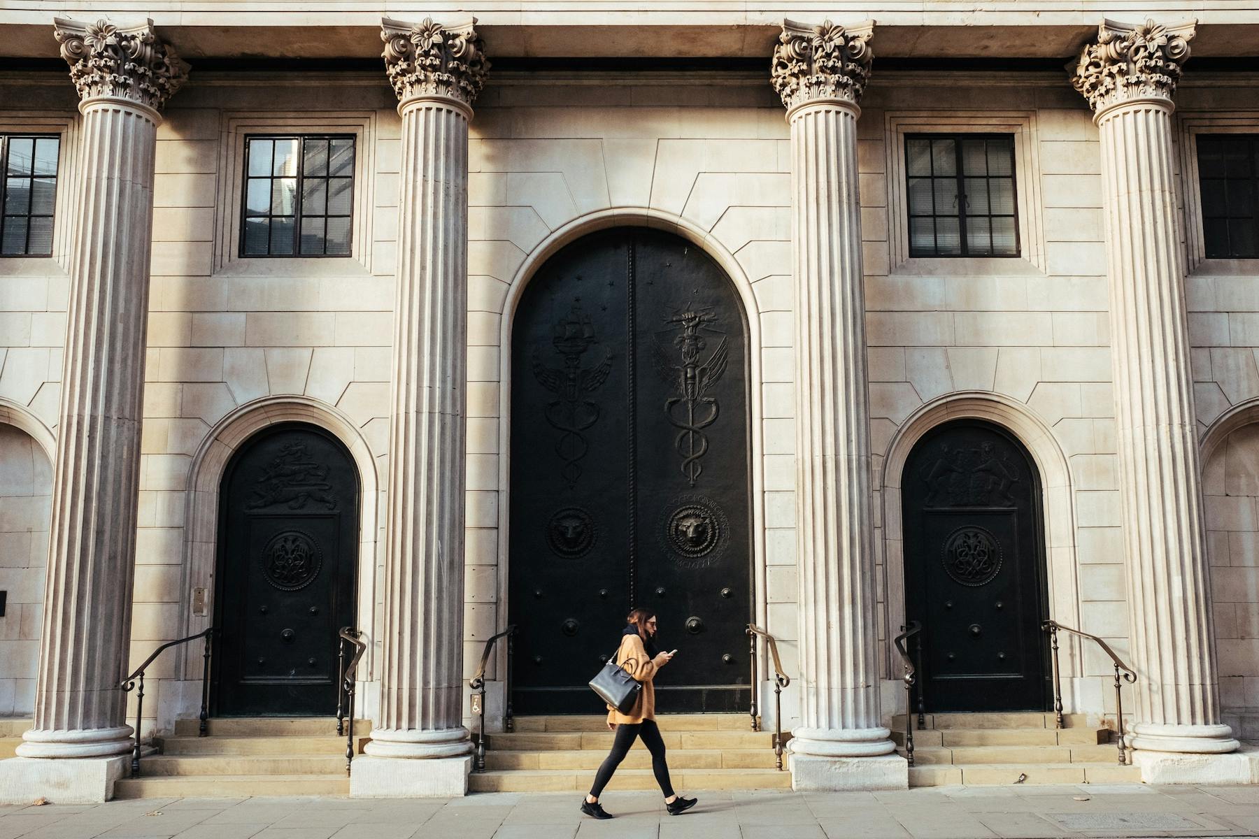 Mulher passando em frente ao portão do Banco da Inglaterra