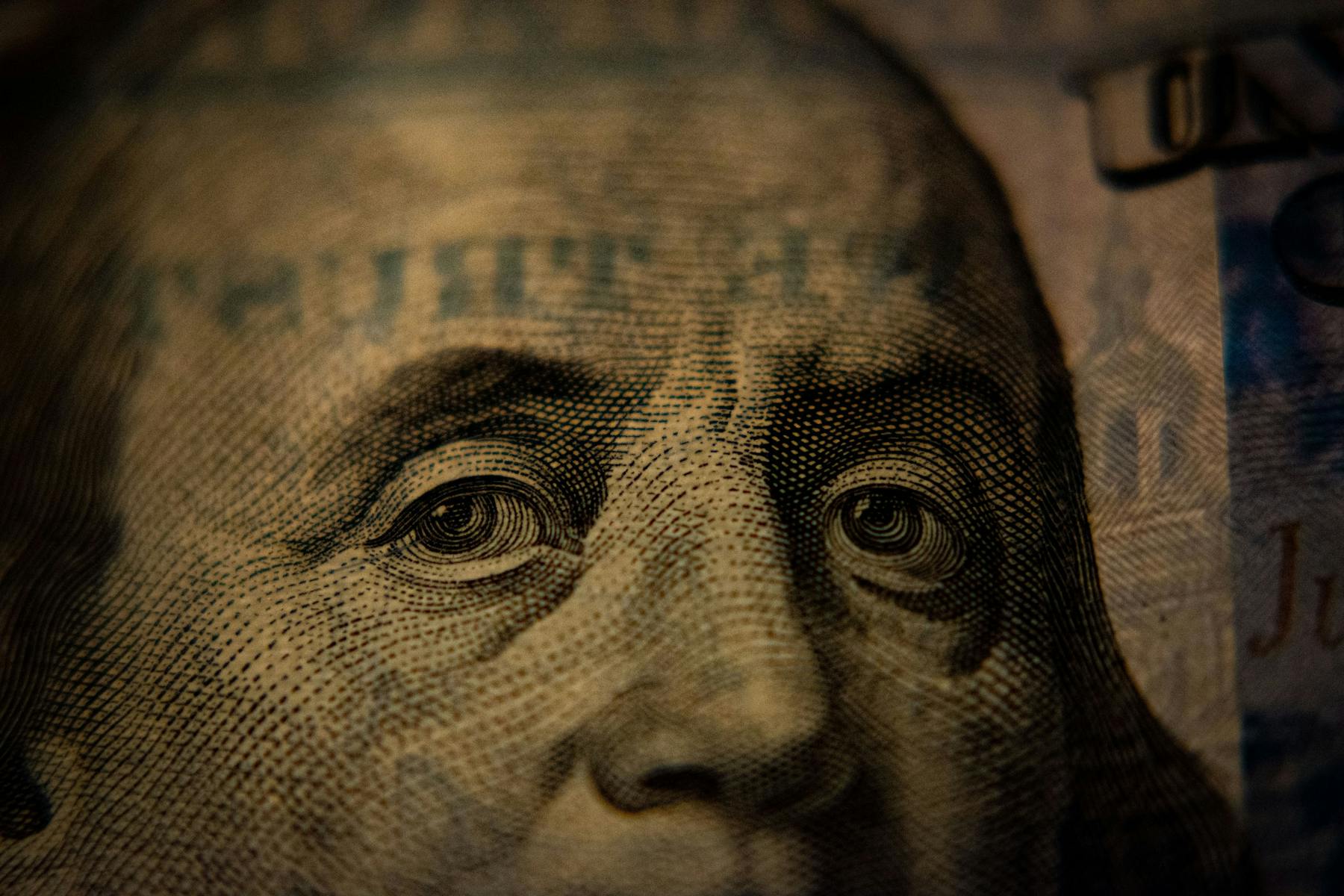 A closeup of Benjamin Franklin's face printed on a hundred-dollar bill.