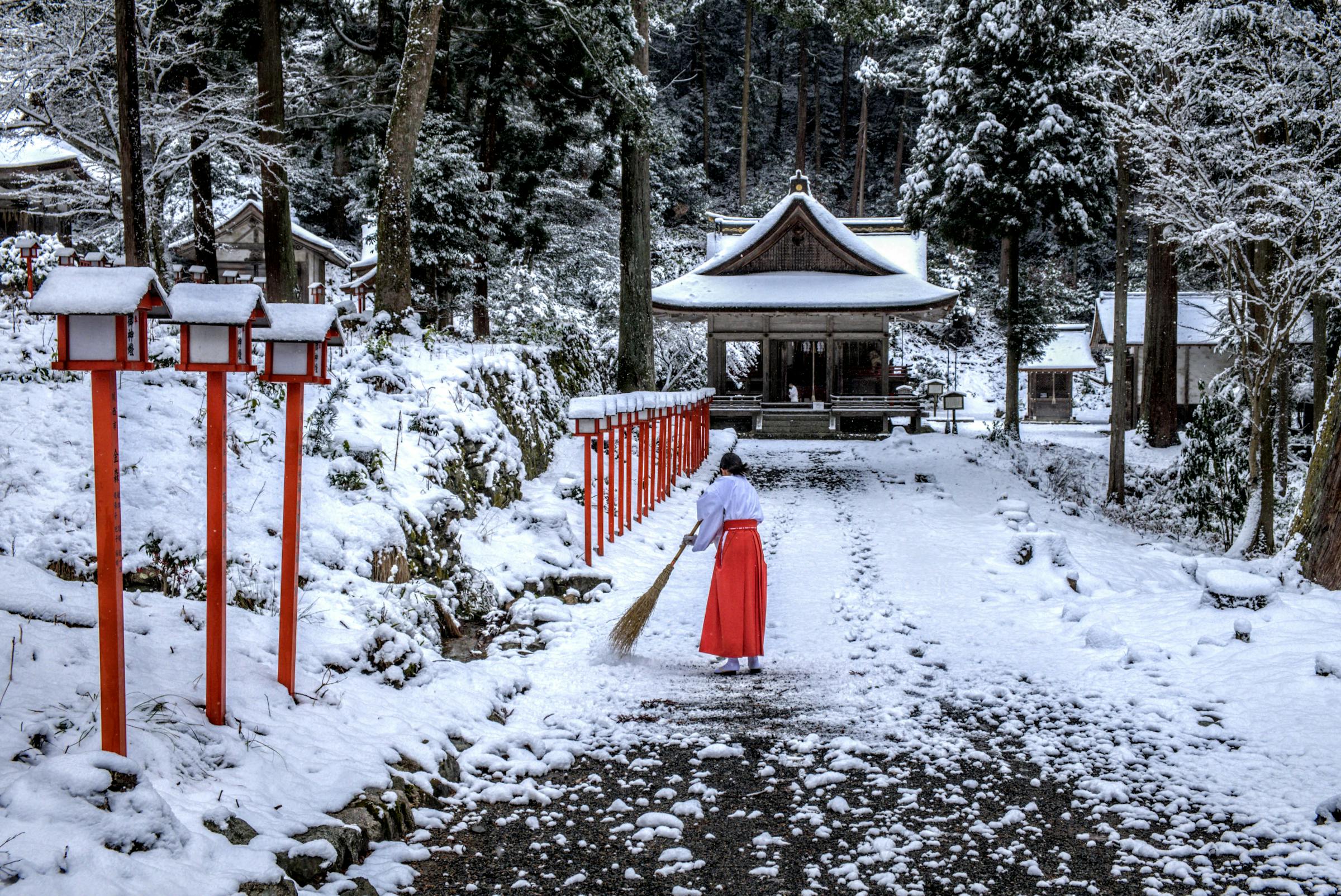 Cleaning fresh snowfall from Hiyoshi Taisha Shrine on Mount Hieizan in Shiga, Japan near the mountains of Kyoto