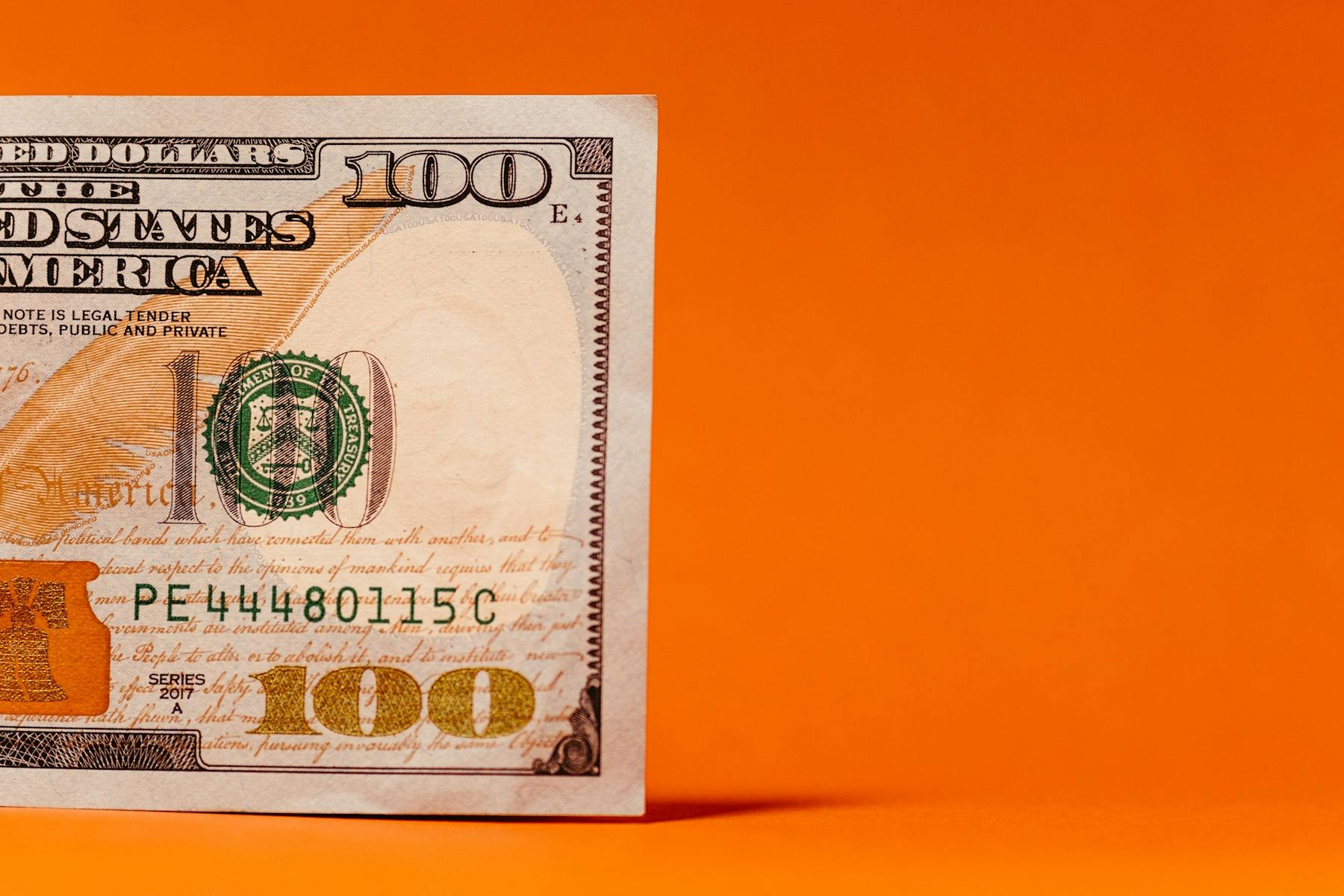 A one hundred dollar bill on an orange background