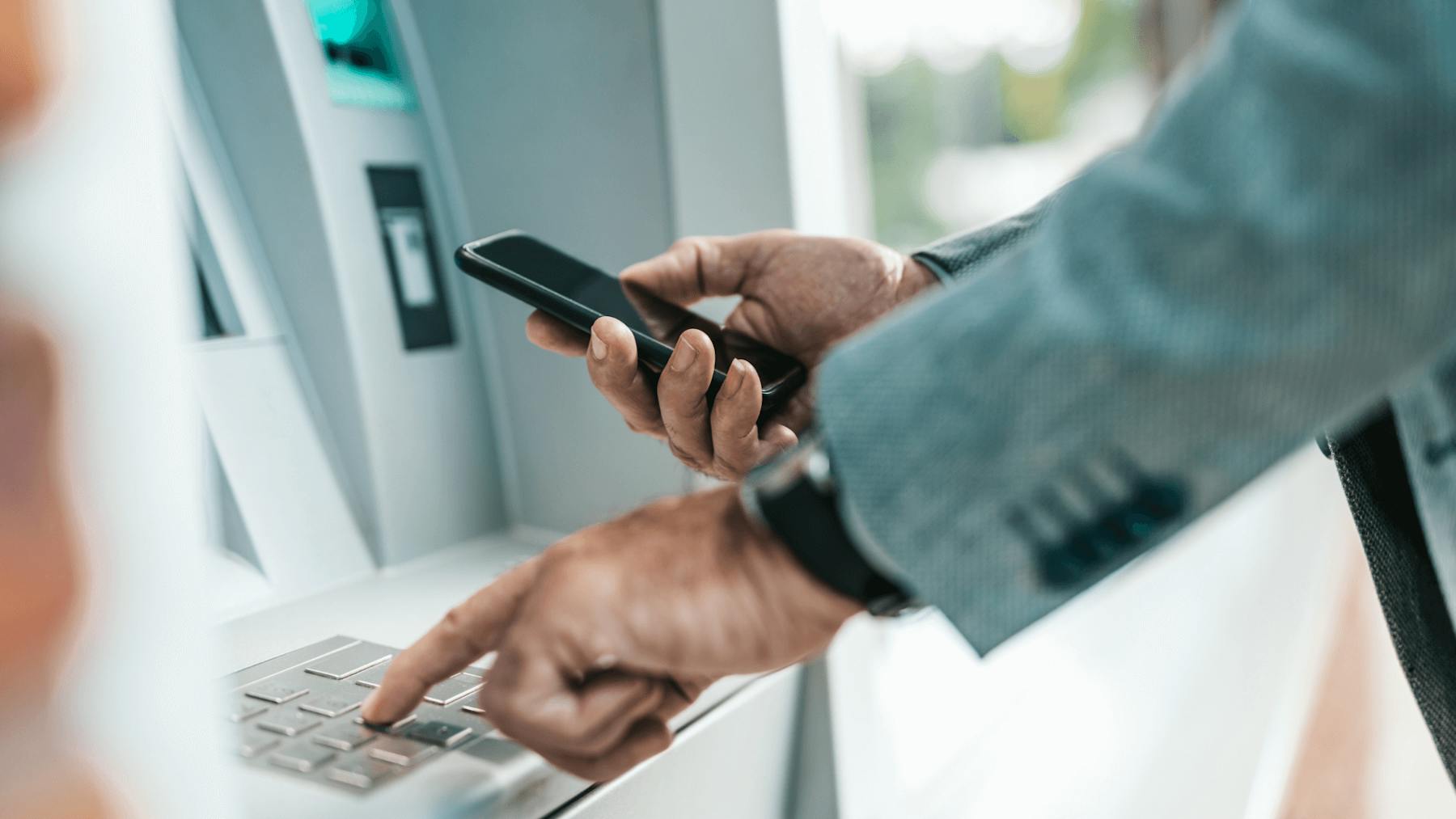 Homem utiliza o celular para sacar dinheiro em um caixa automático