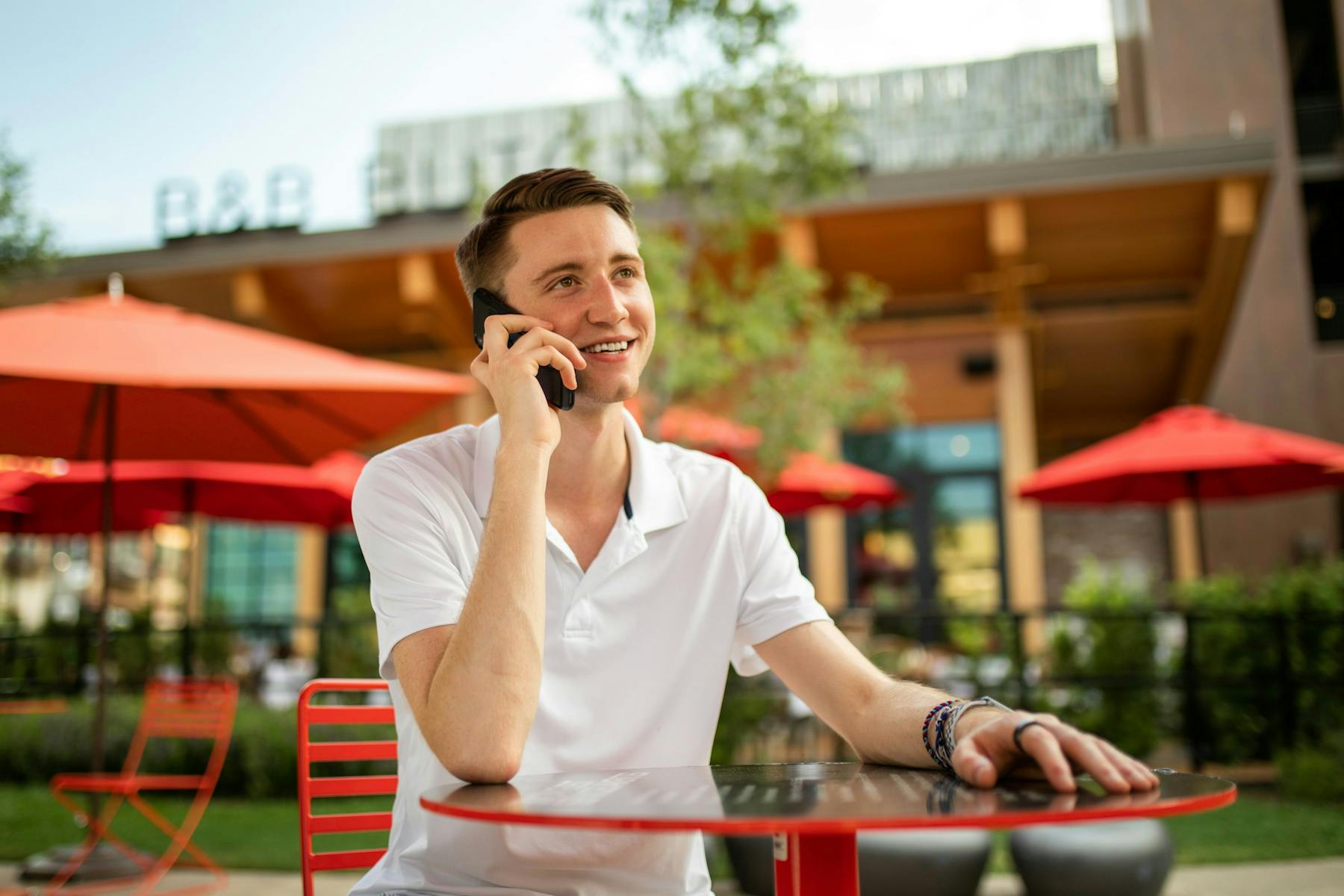 A man in a white crew neck t-shirt sitting on the phone