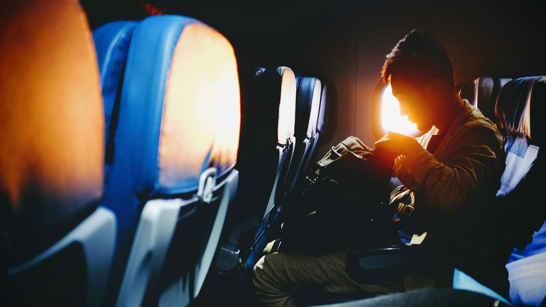A man looking into his bag while in an airplane